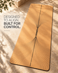 A tan yoga mat with black line art and the brand name 'GURKHA' printed down the center, laid diagonally on a sunlit stone surface with shadow overlays. Text on the left reads, 'DESIGNED TO ALIGN.